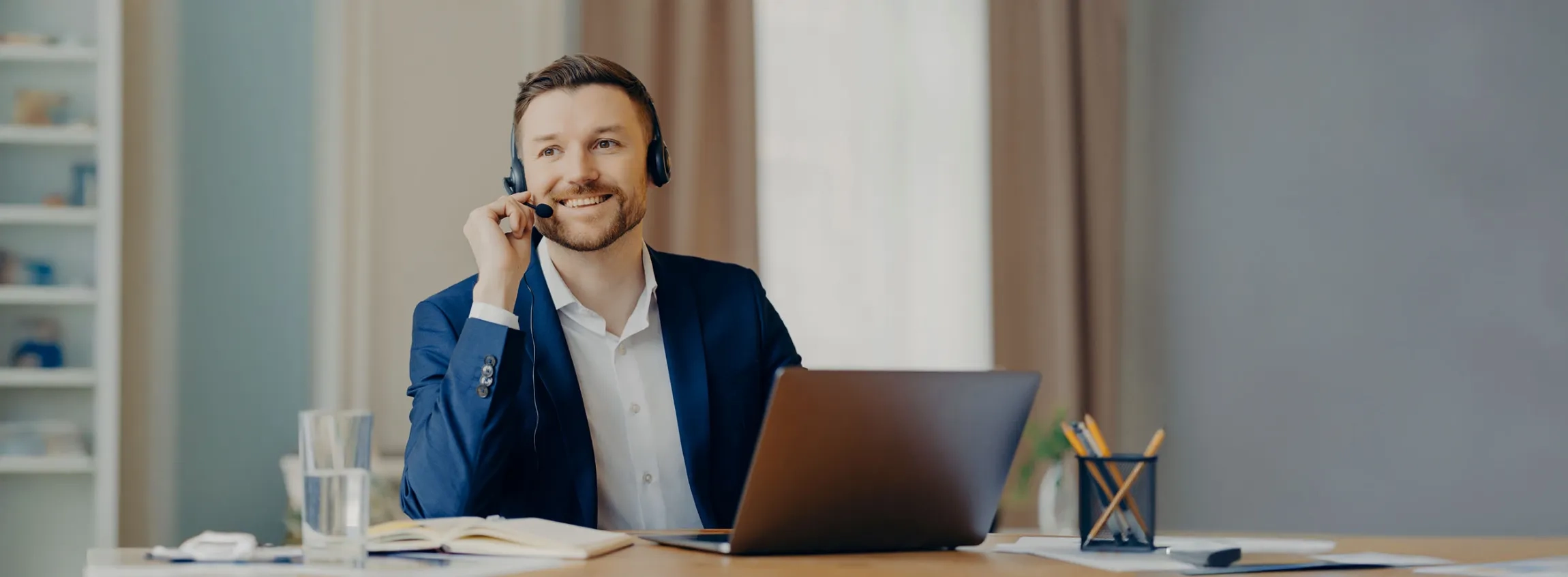 Telefonierender Mann mit Headset und Laptop im Büro