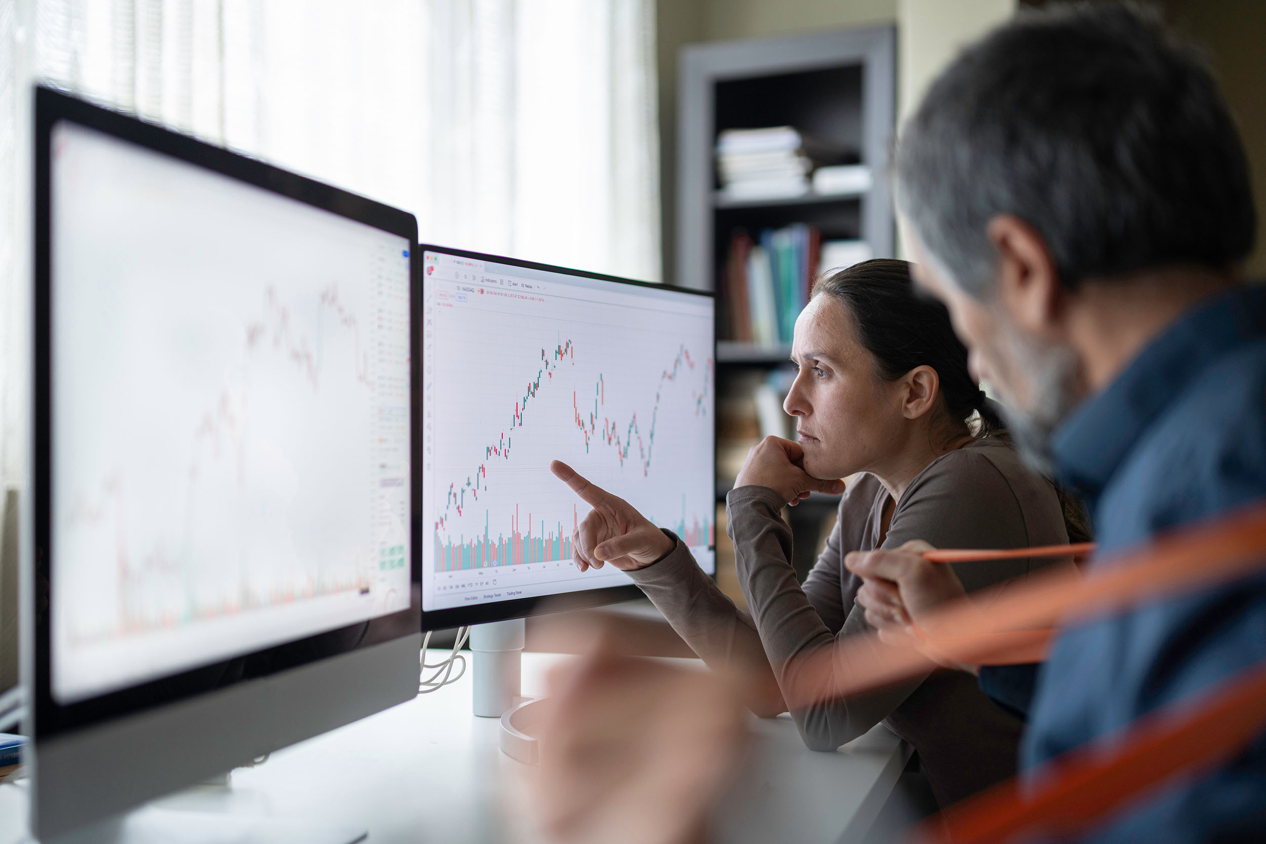 zwei Personen an Monitoren mit Charts